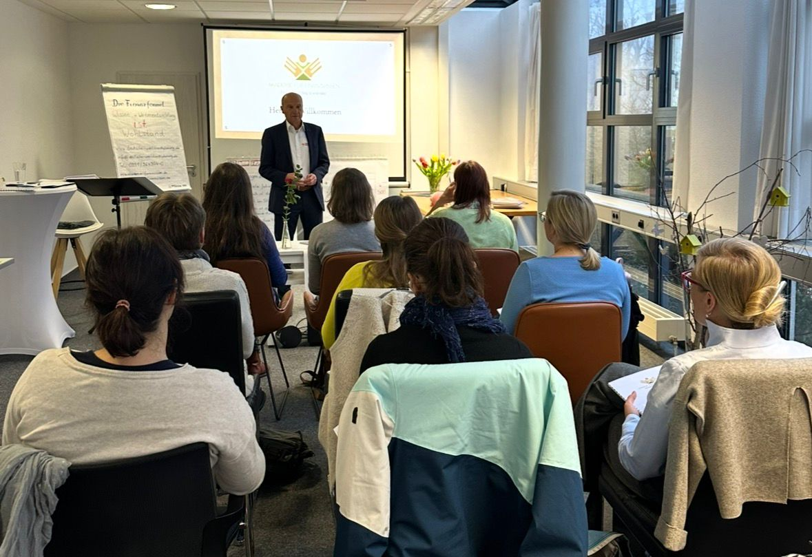 Teilnehmende im Seminar an Tischen mit Unterlagen